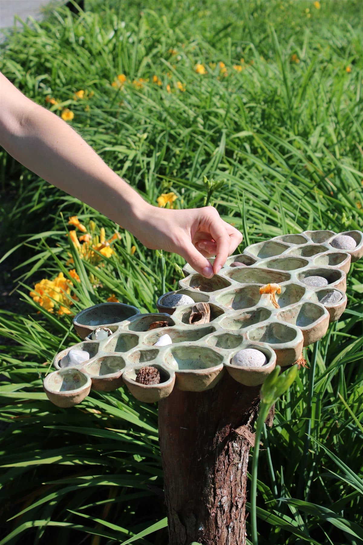 Vessels by Denise MacLean, hand-formed clay pockets holding natural objects at the Fredericton Botanic Garden